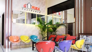 A hotel lobby with colorful chairs, a reception desk, and a large mirror reflecting the interior. - Gapura Residence By Sinergi (Semarang)