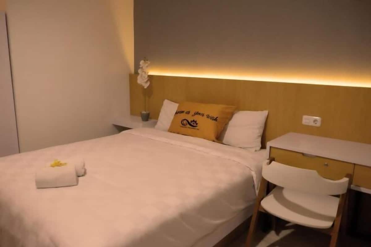 A hotel room with a bed, a bedside table, a chair, and a nightstand.