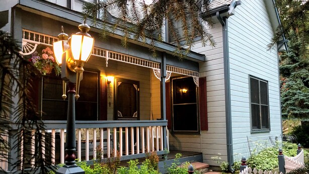 A house with a porch, a white picket fence, and a street lamp.