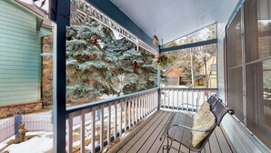 A covered porch with a bench, a stone wall, and a view of snow-covered trees.