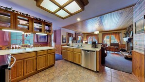 A kitchen with wooden cabinets, a central island, and a dining area with a table and chairs.