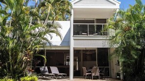 A two-story building with a white exterior, large windows, and a balcony.