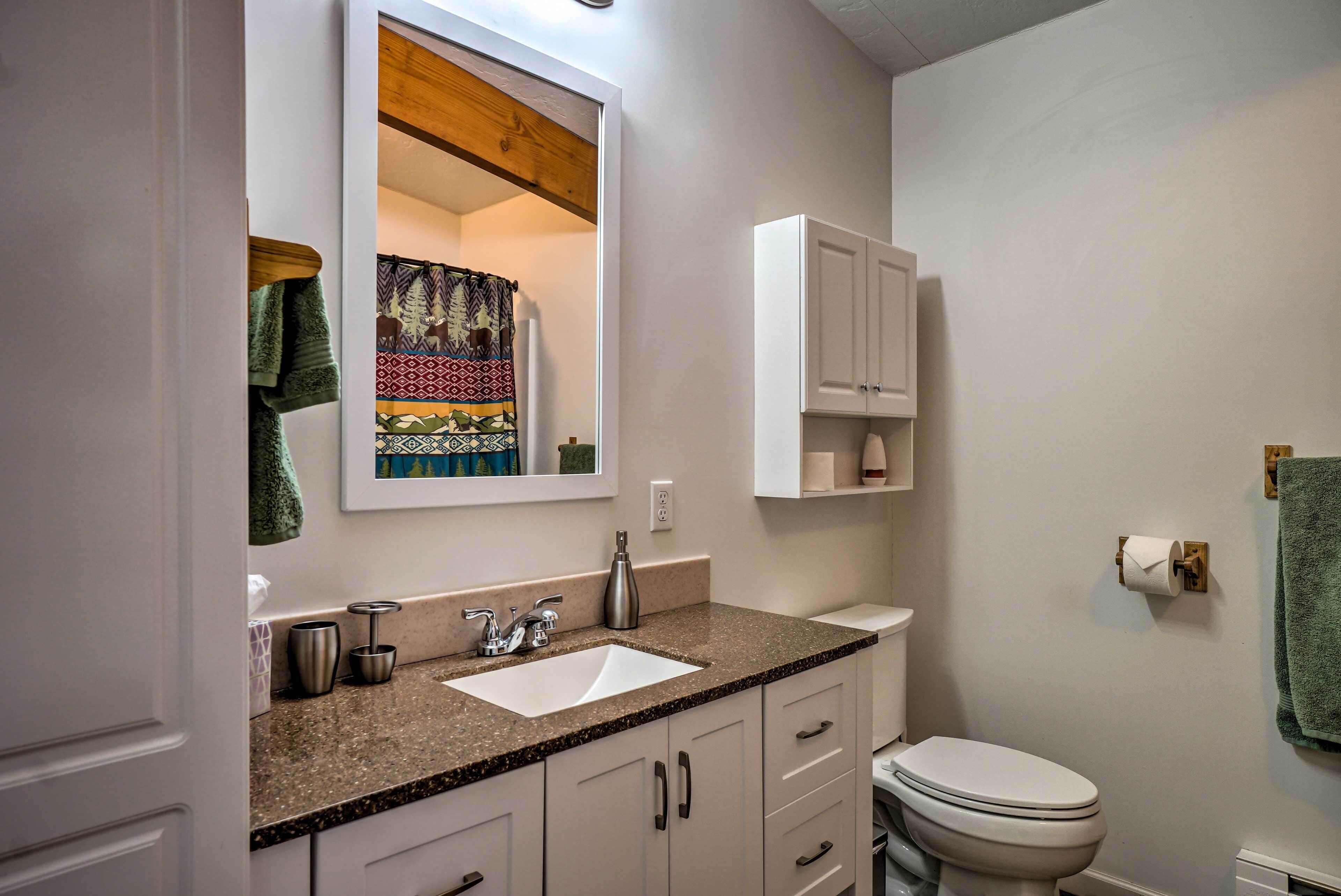 A bathroom with a white sink, a mirror, a toilet, and a cabinet above the sink.