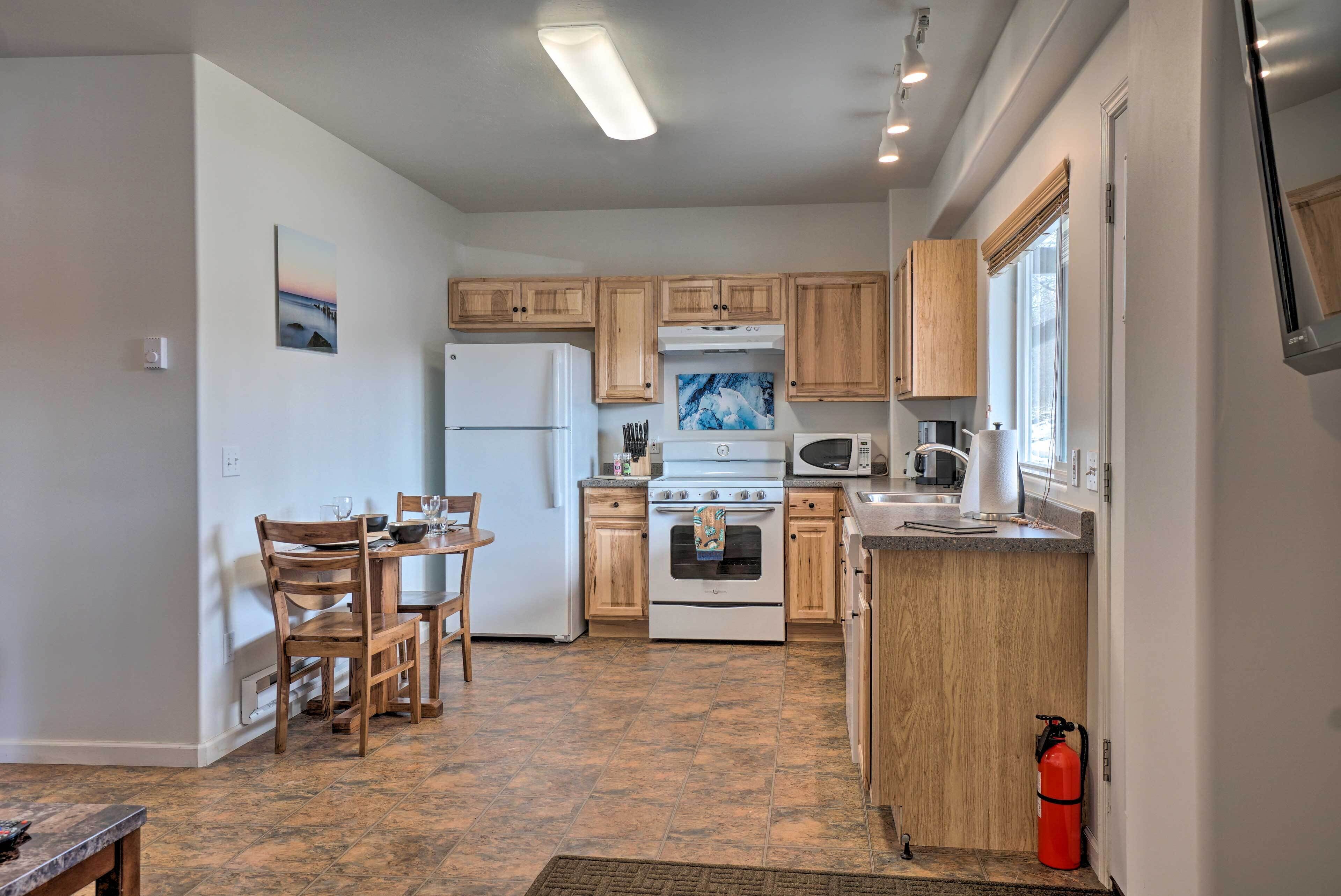 A compact kitchen with wooden cabinets, a white refrigerator, a stove, and a microwave.