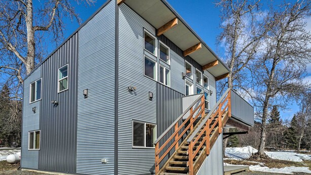 A modern two-story building with a wooden staircase leading to the upper floor. - Homer Hideaway on Fritz Creek! Families Welcome (Homer)