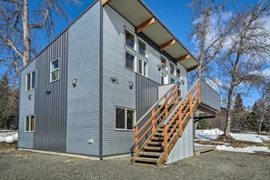 A modern two-story building with a wooden staircase leading to the upper floor. - Homer Hideaway on Fritz Creek! Families Welcome (Homer)