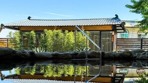 Il s’agit d’un bâtiment japonais traditionnel, doté d’un toit recouvert de tuiles, d’une structure en bois et d’un chemin de pierre menant à un étang.