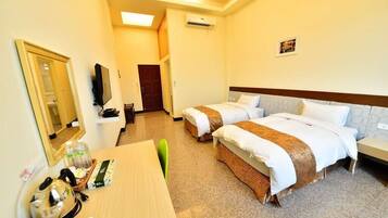Habitación de hotel con dos camas, un escritorio, un espejo, una televisión y una puerta.