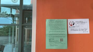 A hotel entrance with a sign indicating room number 87, a green informational sign, and a red anti-sexual harassment notice.