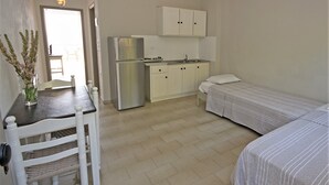 A compact room with a kitchenette, a dining table with chairs, and two single beds. - Home away from home, Apartments Poros Island (Kiani Akti)