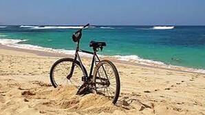 A bicycle parked on a sandy beach with the ocean in the background. - Lively Lofts by The Varos Residences (Lemnos)