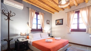 A bedroom with a bed, two bedside tables, a lamp, a coat rack, and a window with curtains. - Lively Lofts by The Varos Residences (Lemnos)