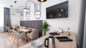 Un comedor moderno con una mesa de madera, sillas, un hervidor y un tazón.