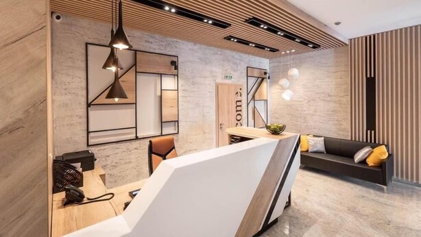 Un área de recepción moderna con un mostrador, un sofá y un cartel en la pared.