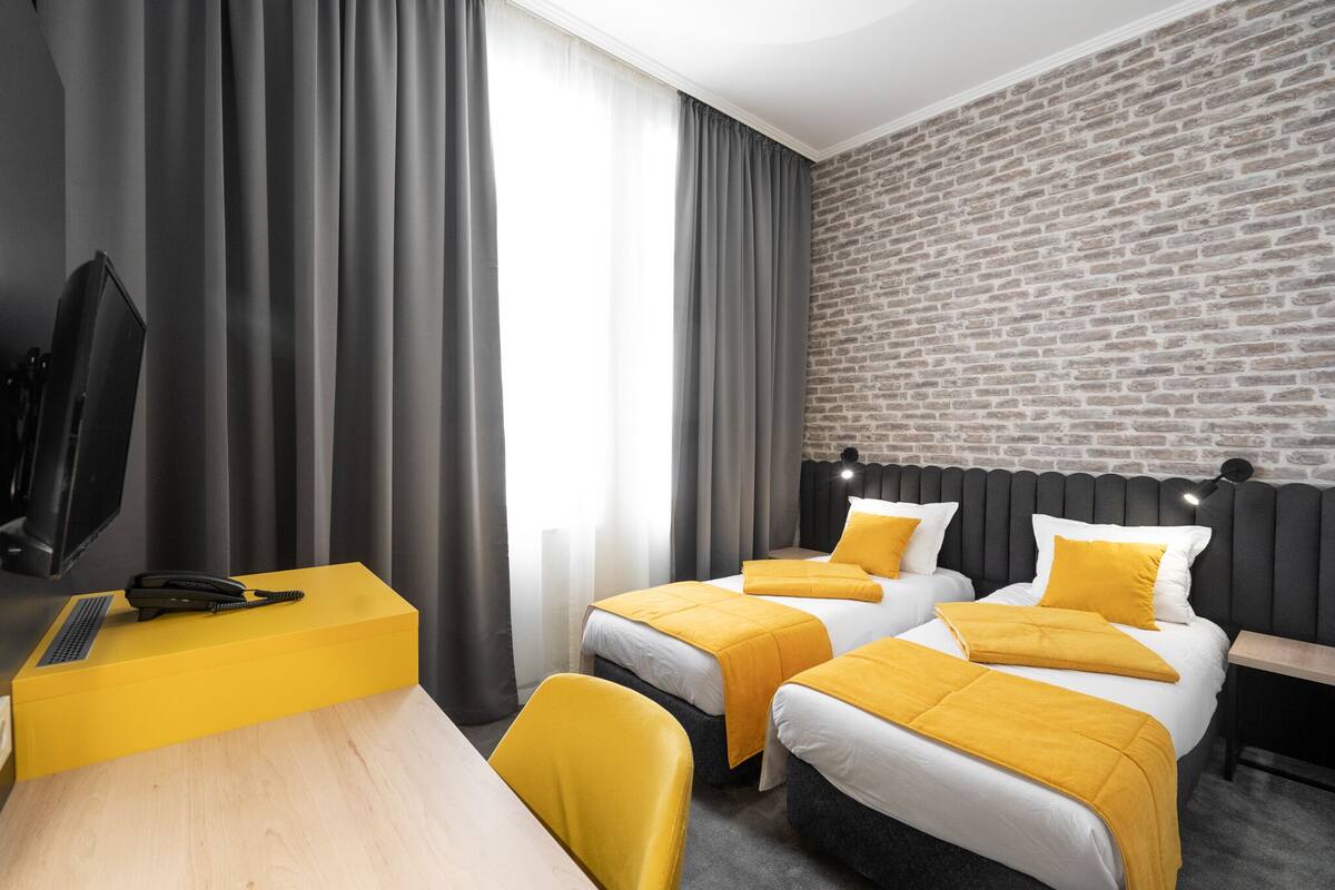 A hotel room with two beds, a desk, a telephone, and a television.