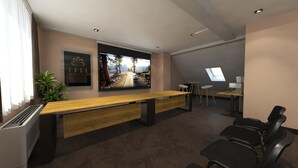 Una sala de conferencias moderna con una larga mesa, sillas, una pantalla grande y un escritorio pequeño con una computadora.
