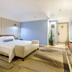 Habitació d'hotel amb llit, taulell de nit i una planta en test.