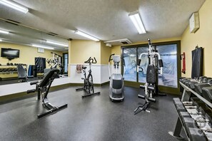 A gym with various exercise equipment, a television, and a large window. - Fernie 2BR Condo / Hot Tub & Mountain Getaways (Fernie)