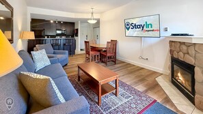 Ein Wohnzimmer mit Sofa, Couchtisch, Kamin und Essbereich mit Stühlen.