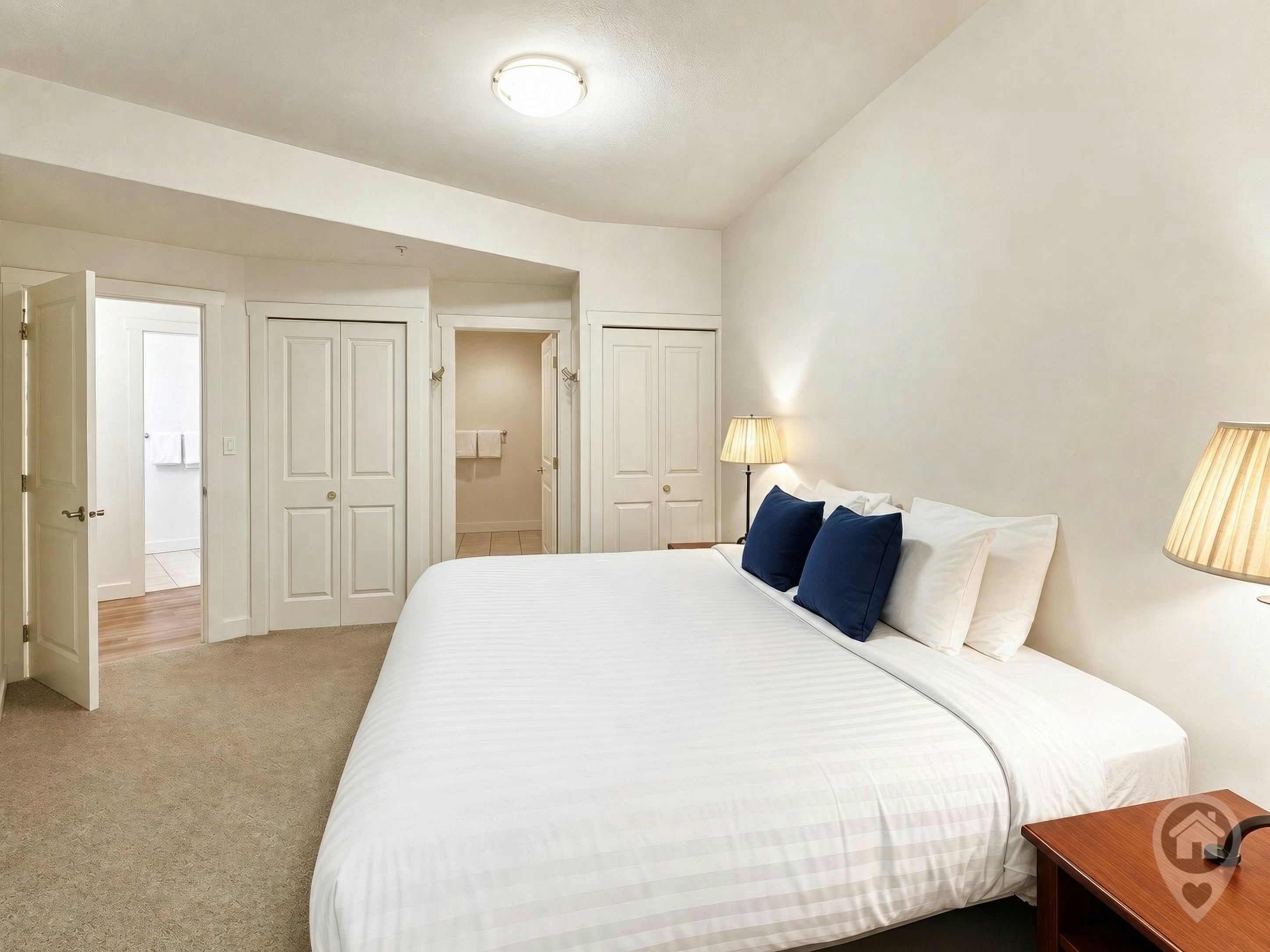 Een hotelkamer met een groot bed, twee bedlampen en een houten nachtkastje.