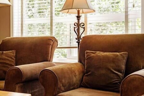 A room with two brown sofas and a floor lamp.