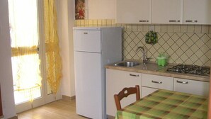 A compact kitchen with a refrigerator, sink, and stove. - Villa Vale Mery (Vieste)