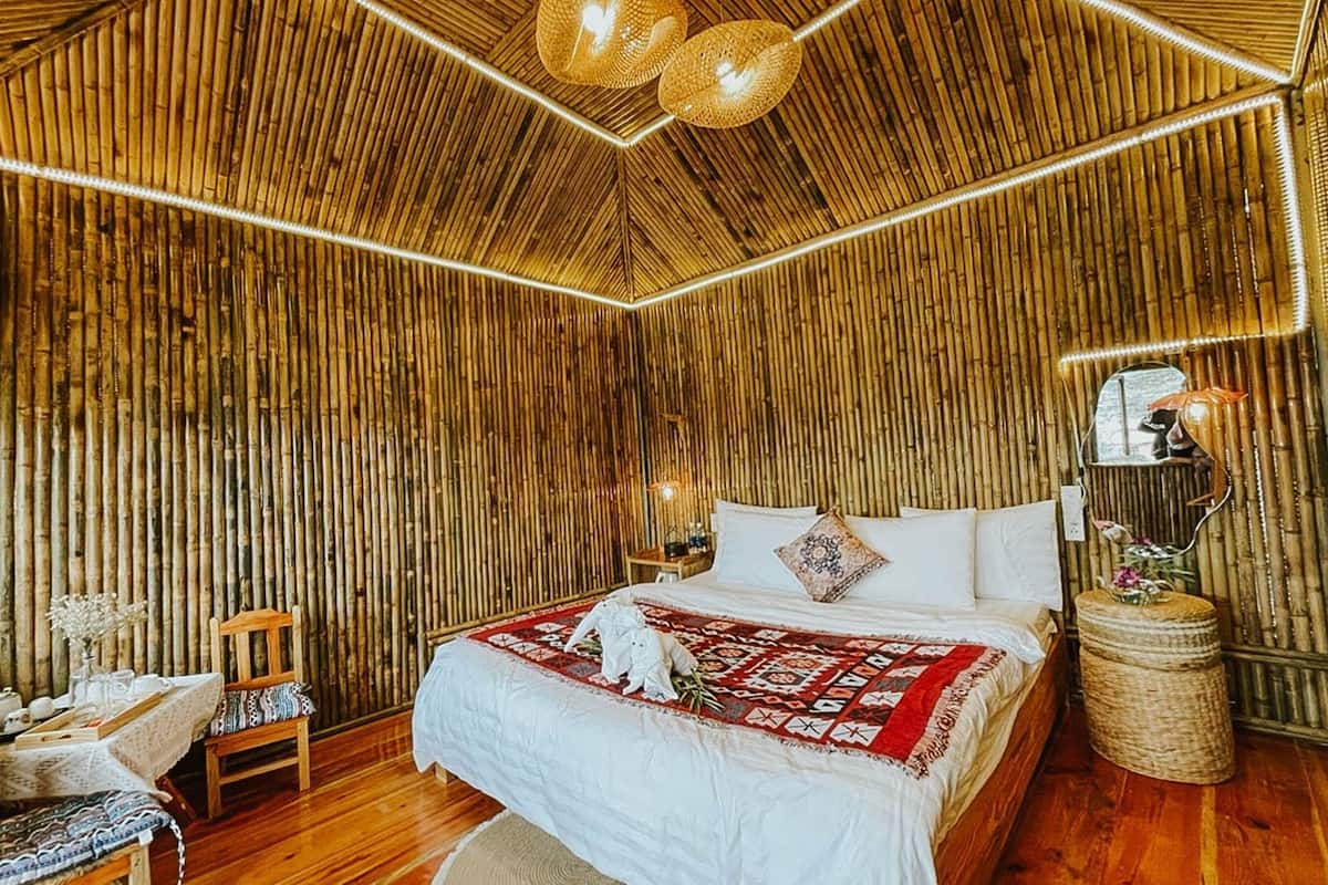 Ein Zimmer mit einem Bett, einem Sessel, einem kleinen Tisch und einer Lampe.