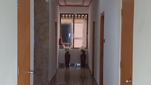 A hallway with marble flooring, wooden doors, and a window with decorative elements. - Hotel Dralha (Thimphu)
