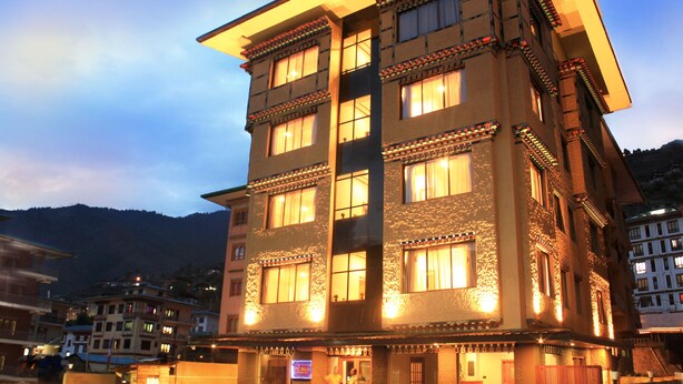 A multi-story hotel with traditional architectural design, featuring multiple windows and balconies. - Hotel Dralha (Thimphu)