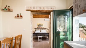 Um quarto aconchegante com uma cama, uma cadeira de madeira, uma mesa pequena e uma porta verde.
