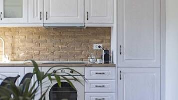 A kitchen with white cabinets, a brick backsplash, and a coffee machine.
