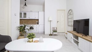 Una cuina moderna amb armaris blancs, un salvasalls de rajola i una zona de menjador amb taula blanca.