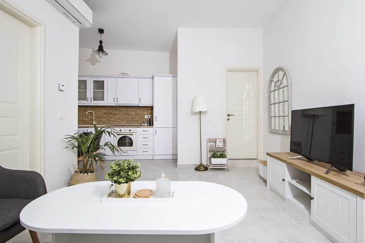 A modern kitchen with white cabinets, a brick backsplash, and a dining area with a white table.
