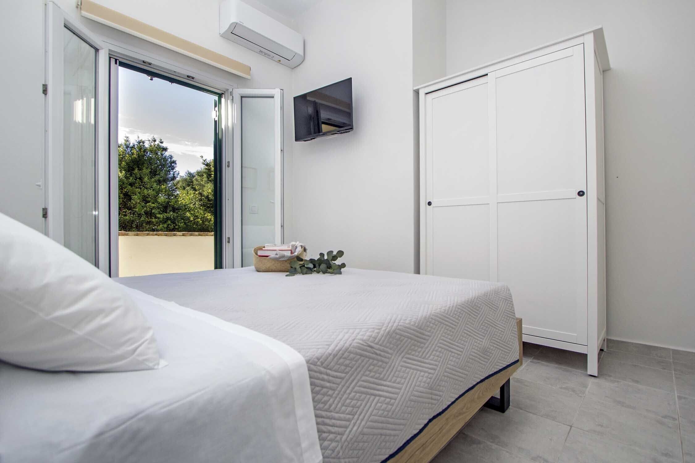 Un dormitorio con una cama, un televisor montado en la pared y una puerta corredera.