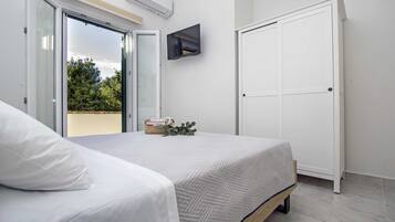 Un dormitorio con una cama, un televisor montado en la pared y una puerta corredera.