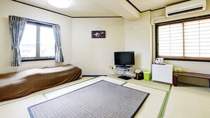 A room with a bed, a television, a small table, and a window with curtains. - Arks Inn Omori (Ube)