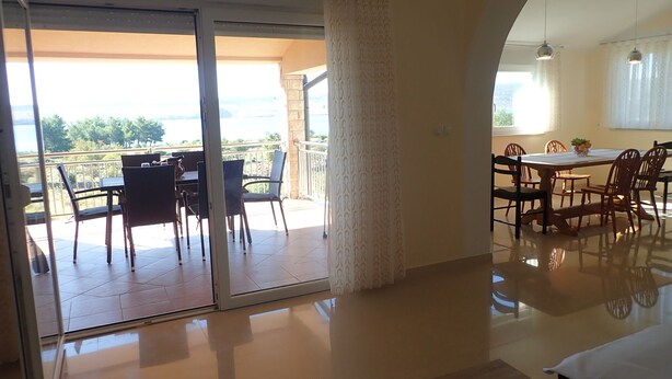 A modern hotel room with a balcony, a dining area, and a large bed.
