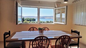 A dining area with a table, chairs, and a view of the sea through large windows.