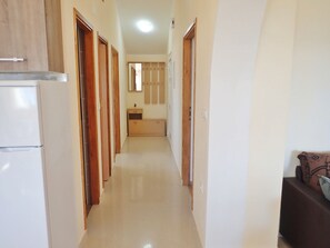 A narrow hallway with wooden doors, a kitchenette area, and a sofa in the foreground. - Comfortable apartment for 6 people with a view of the sea (Seline)