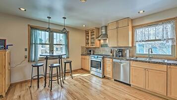 Une cuisine moderne avec des meubles en bois, un four encastré, un lave-vaisselle et une fenêtre donnant sur l’extérieur.