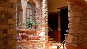 A stone-walled interior with a staircase leading to a higher level. There are wooden chairs and a table, suggesting a dining area. - Country House La Posada Del Río Carbo. (Villahermosa del Río, España –)