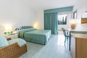 Ein Hotelzimmer mit Bett, Schreibtisch, Stuhl und einem fensterbepflanzten Fenster.