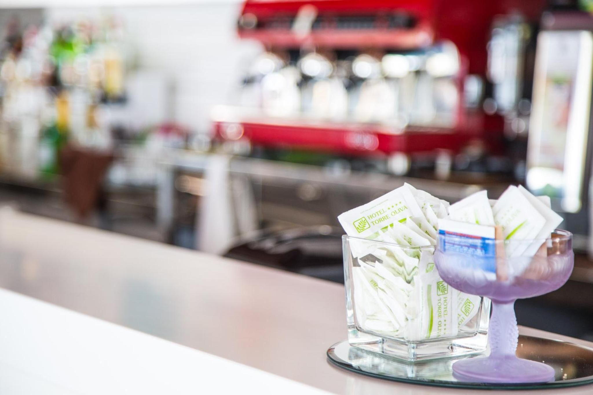 Un récipient en verre contenant des brochures d’hôtels, posé sur le comptoir d’un bar.