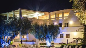 A nighttime pool area with lounge chairs and a building in the background. - Hotel Torre Oliva (Santa Marina)