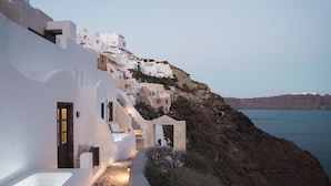 A coastal hotel with white buildings, a stone pathway, and a view of the sea. - Armenaki -  Adults Only (Santorini)