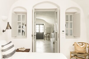 Um quarto com uma cama, uma mesa de cabeceira, uma luminária, uma cadeira e uma bolsa com a palavra 'Armenia'.