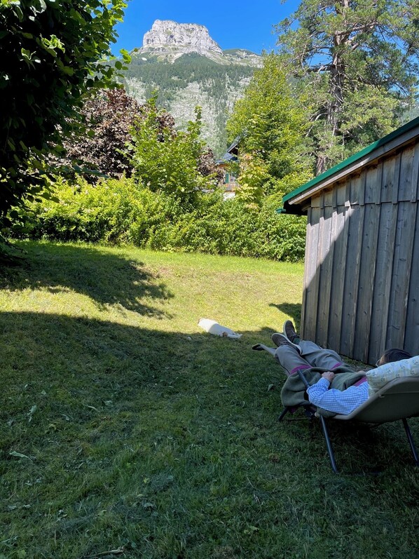 Una casetta in legno con tetto verde, un'amaca e un cane sdraiato sull'erba.