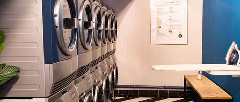 A laundry room with multiple washing machines, a sink, and a checkered floor.