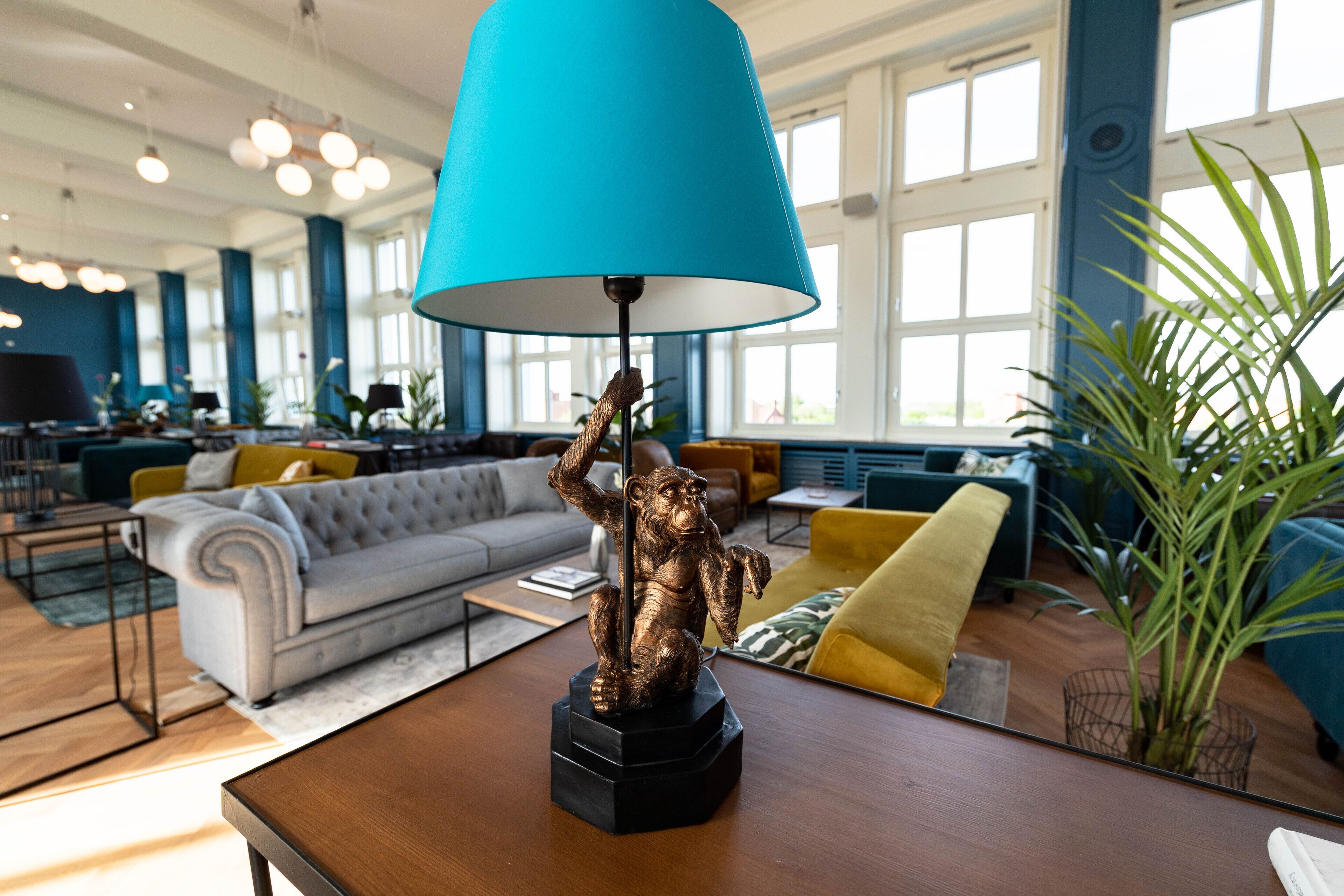 En moderne stue med en stor blå lampe, en polstret sofa og en dekorativ abe statue på et træbord.