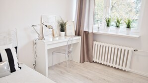A modern bedroom with a white desk, clear chair, and a radiator. - Warsaw Concierge Opera Apartment (Warsaw)